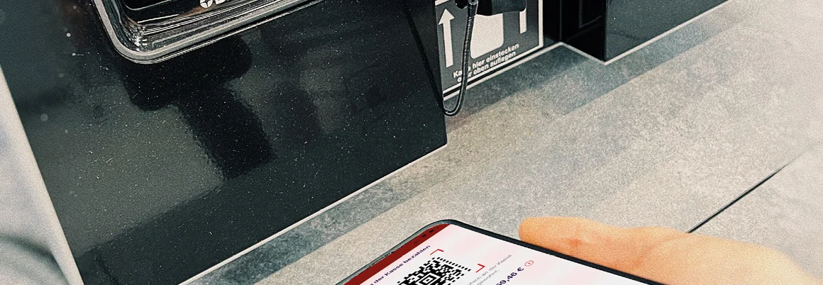 Person scannt QR-Code auf Smartphone an einem Kassenterminal